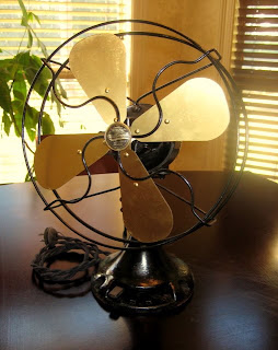 Restored antique brass-blade fan with polished guard, blades and renewed black base.