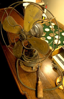 Antique brass-blade fan before restoration, showing age, oxidation and worn finish.