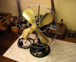 Restored antique fan with brass blades, bright guard and refinished dark base.