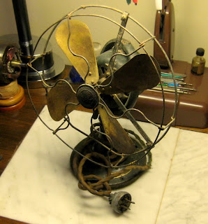 Heavily worn antique desk fan before restoration with aged cage, blades, wiring and finish.